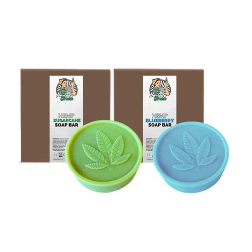 Two circular Lady Green Hemp Soap Bars from Green Apron are displayed in front of their packaging. The left soap bar, labeled 